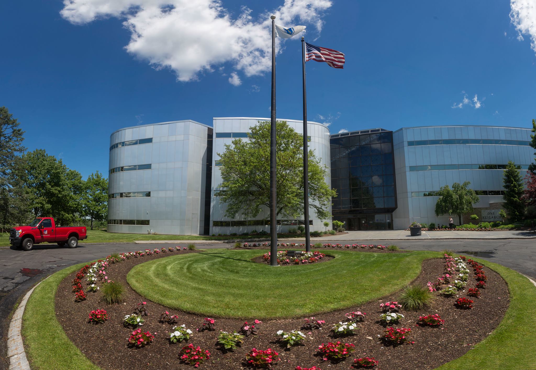 Grass and flowerbeds landscaped around 2 flag poles outside a business.