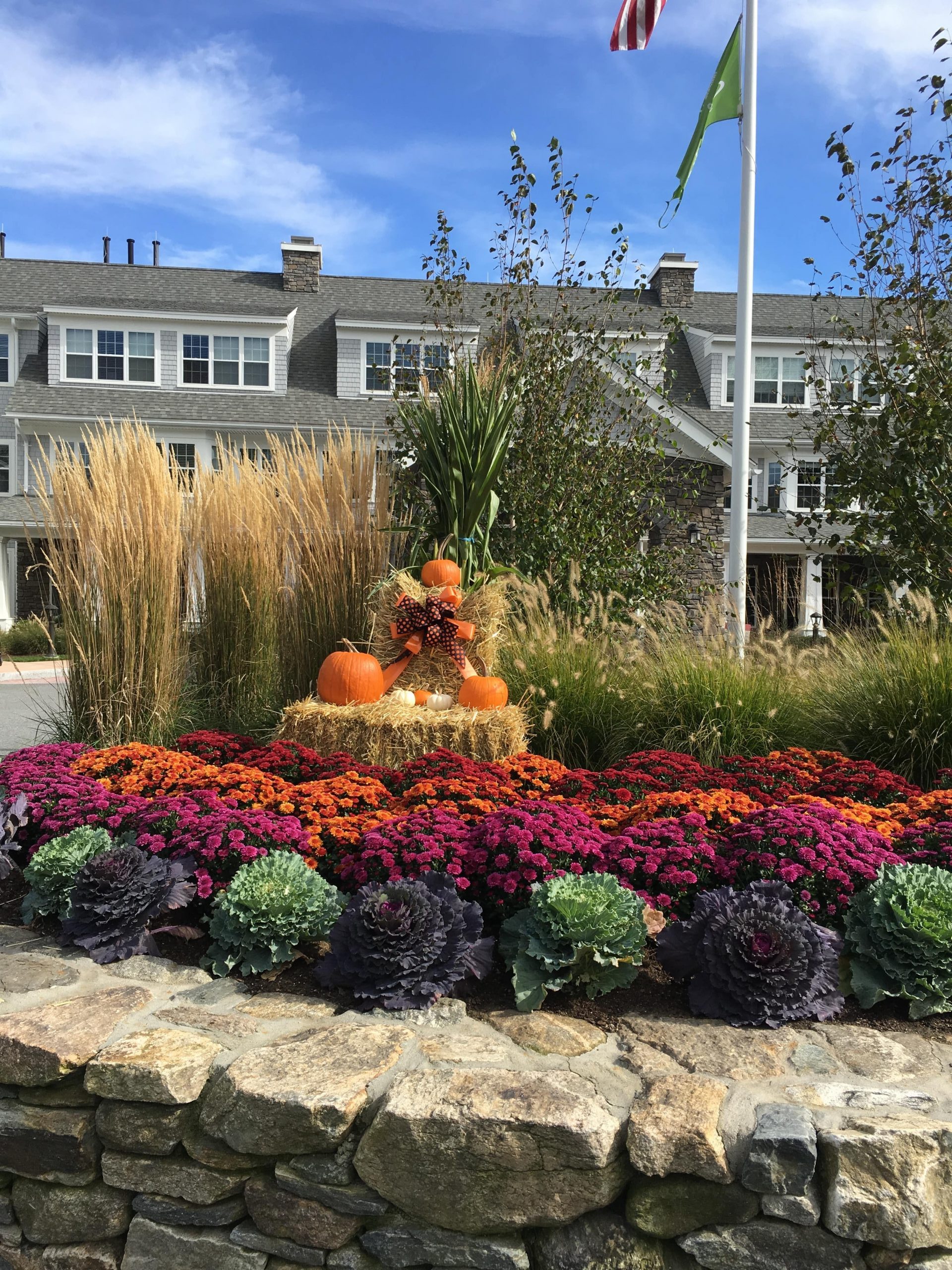 Fall landscaping display complete with pumpkins, flowers, and hay.