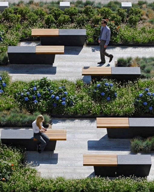 Offset benches surrounded by landscaped flower beds in a commercial area.